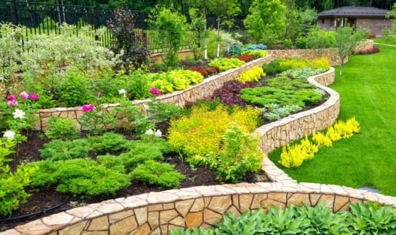 Terraced stone beds with layered plantings and manicured lawn